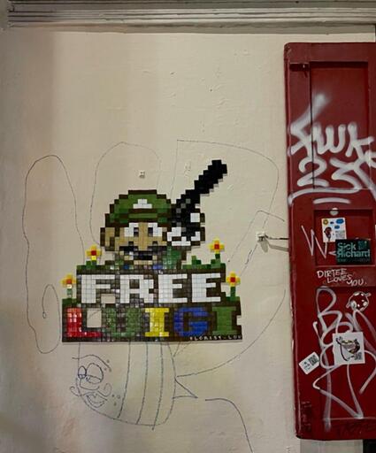 A pixel-style tile mosaic, featuring some small yellow flowers and Luigi the Plumber holding a handgun with a silencer up, alongside the text "Free Luigi"